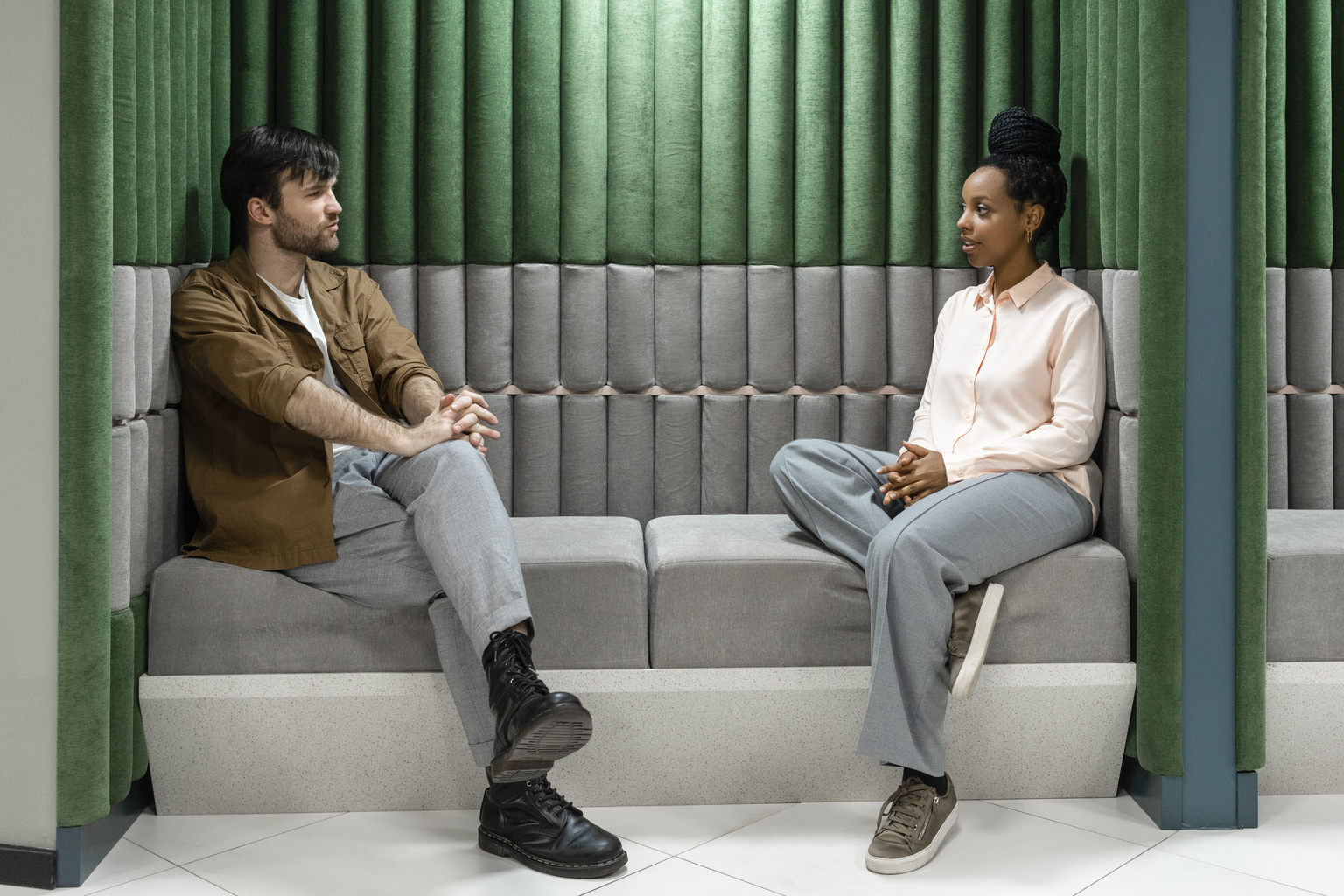 Creative male and female colleagues discussing while sitting on sofa at work place