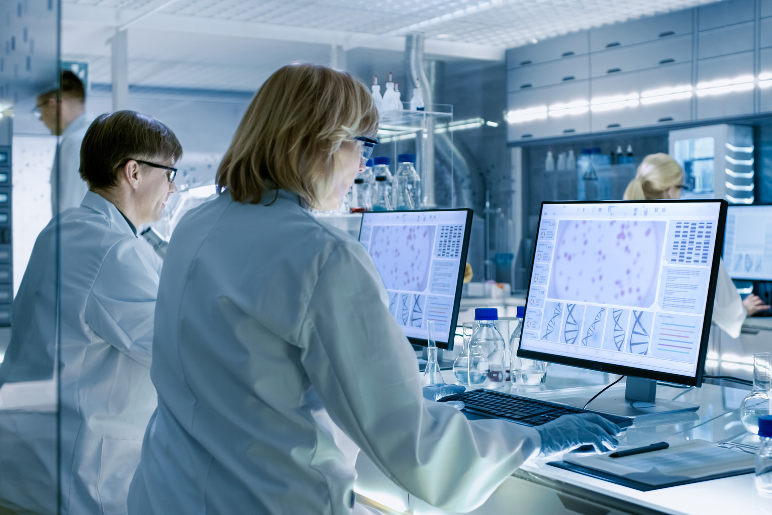 Female and Male Scientists Working on their Computers In Big Modern Laboratory